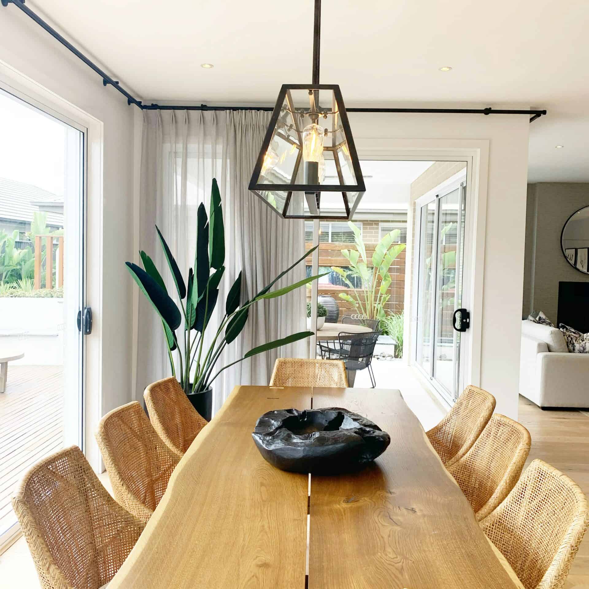 Bright dining room with wooden table, rattan chairs, and large windows.